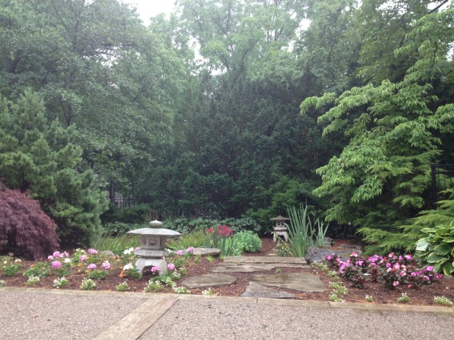Beautiful layers of green form the perfect backdrop for this garden with stone lanterns, paver stepping stones, and Japanese maples.
