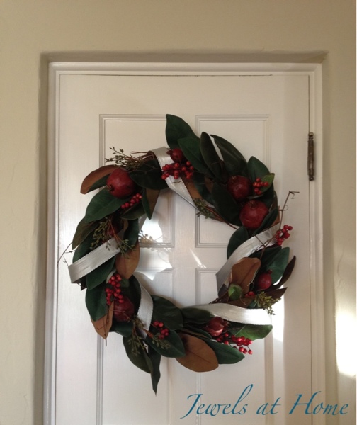 Simple magnolia and pomegranate wreath dressed up with silver ribbon. Christmas house tour from Jewels at Home.